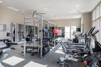 A spacious gym with a variety of equipment including treadmills, stationary bikes, and weight racks.